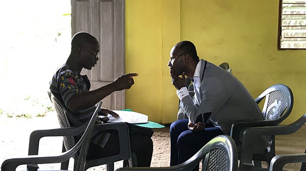 Two men seated and talking.