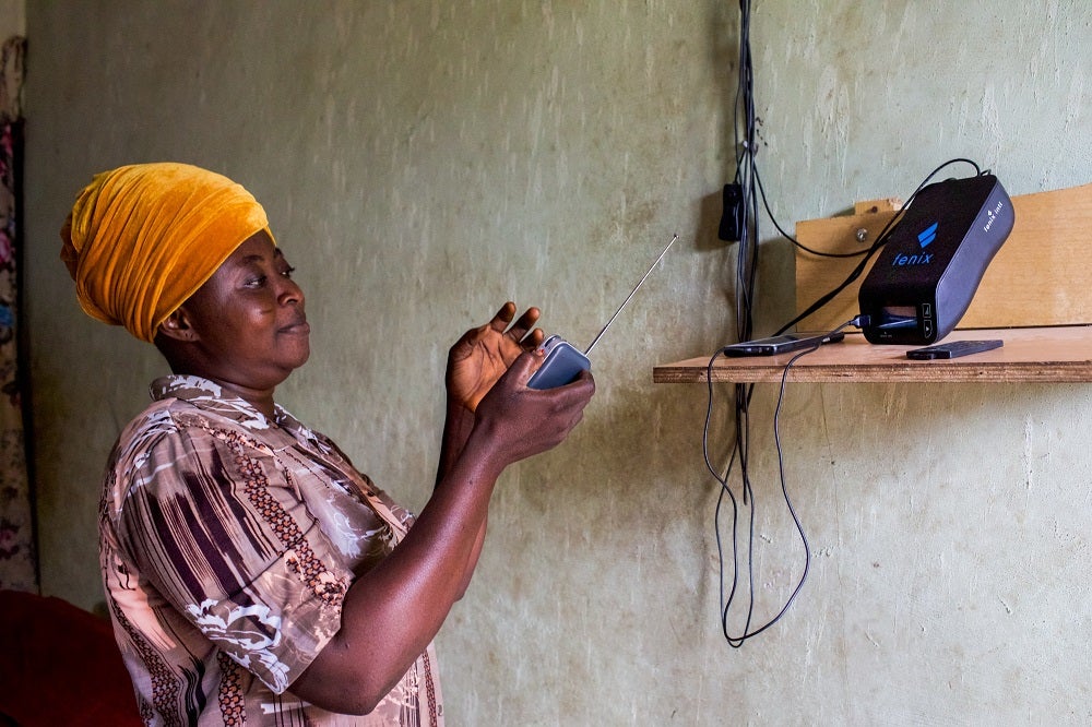 Toyin Ofara, a housewife and mother of three in Lagos, Nigeria, listens to a radio powered by her family’s PAYGo home solar system.