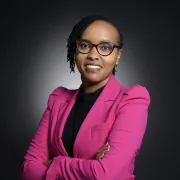headshot of woman in pink jacket against a dark background
