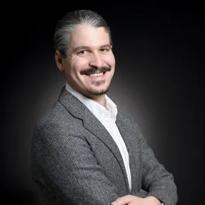 headshot of man in a gray suit