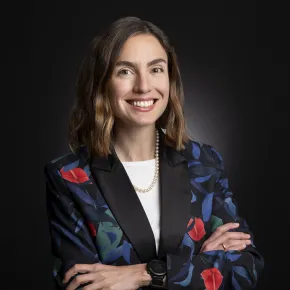 headshot of woman in a colorful jacket against dark background