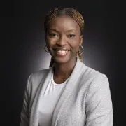 headshot of woman in light blazer against dark background