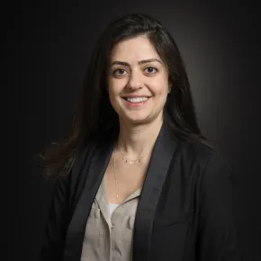 headshot of woman in cream shirt and black blazer against dark background