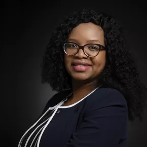 headshot of woman in black jacket against dark background