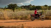 A man rides a motorbike on a rural dirt road