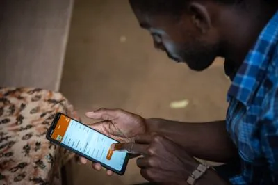 A man using his mobile phone to place a food order from home to a restaurant