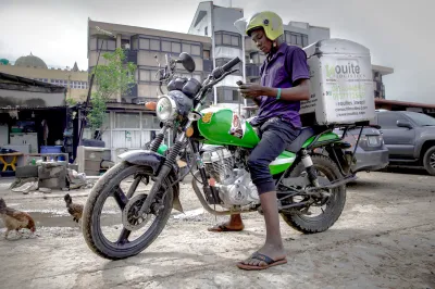 a man on a motorbike, on his phone preparing to make a delivery 