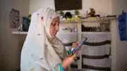 A woman shop owner looks at her smartphone