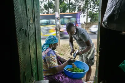 a man shows a female famer details of a mobile money transaction on their phones