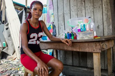 A young woman sits beside her nail salon