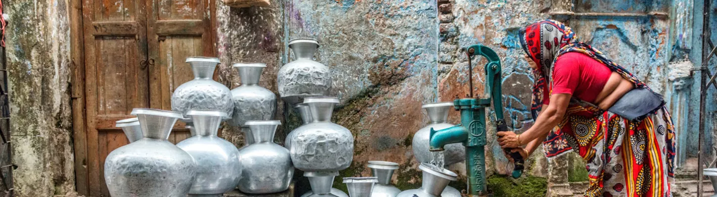a woman fills up a jug of water at a water station in Bangladesh