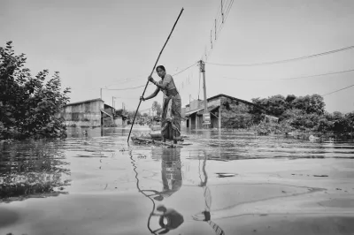 woman in a sari rowing on a flooded street