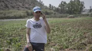 A farmer talks on his mobile phone standing in the field