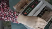 A hand counts money from a till
