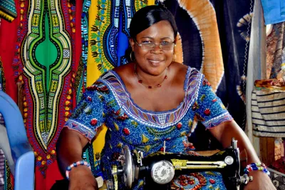 a woman in traditional Ghanian clothing in front of a sewing machine