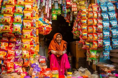 a woman in india sits in front of her small tuck shop