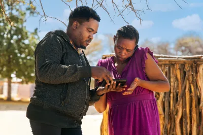 a man shows a woman something on a phone in a rural african village