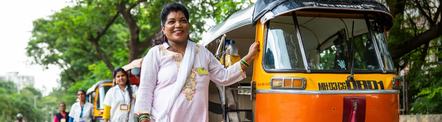 women stand outside their rickshaws
